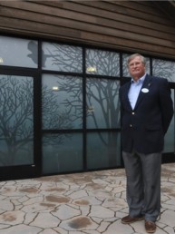Dr. Daniel Klem Jr. stands in front of a building whose windows are covered in decals to help protect and save millions of birds from flying into windows.